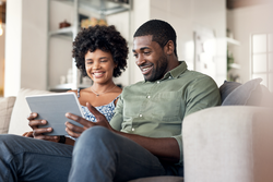 Shot of a young couple using a digital tablet together on the sofa at home